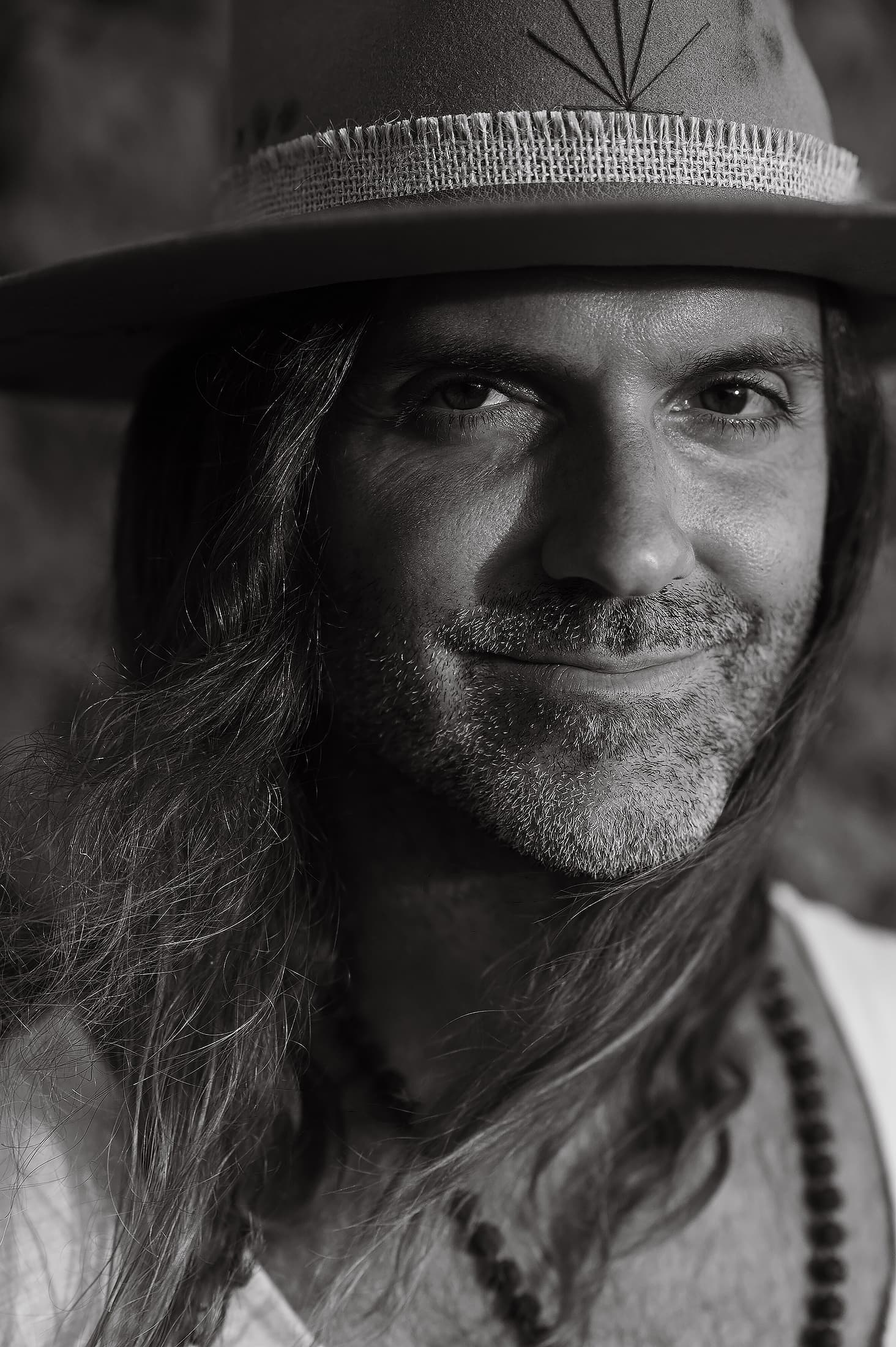 Portrait of director Daniel Bellone in a wide-brimmed hat, black and white.